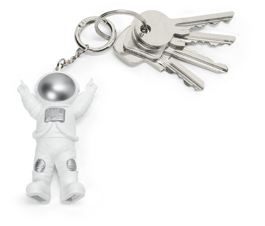 Kľúčenka s malou figúrkou astronauta v bielom obleku a striebornou helmou, pripojená ku zväzku strieborných kľúčov.