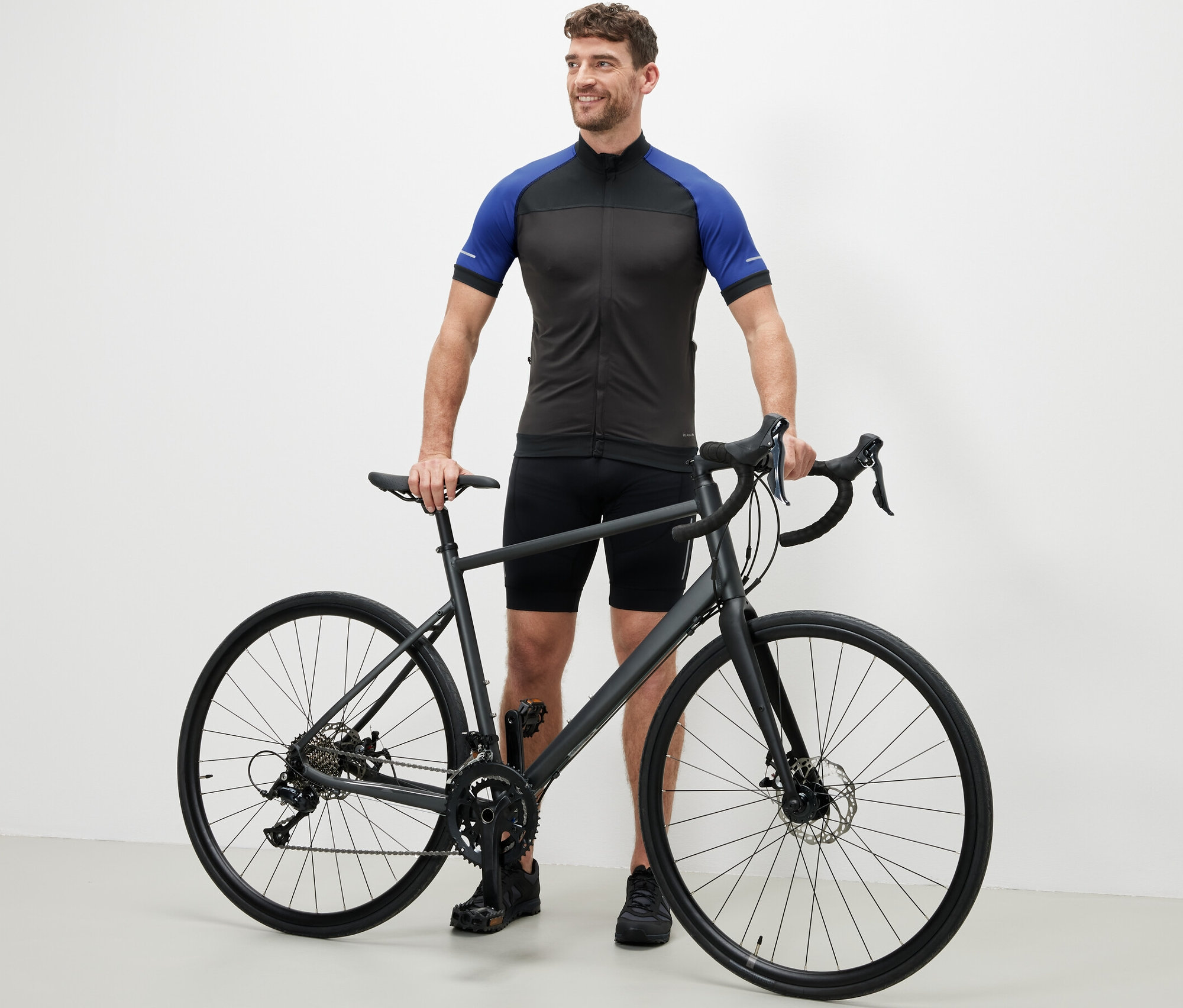 Muž stojí vedľa bicykla v modrom cyklistickom drese.