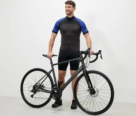 Muž stojí vedľa bicykla v modrom cyklistickom drese.
