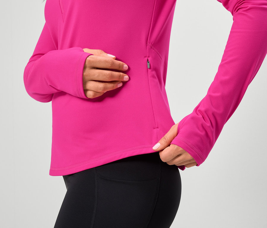 Žena má na sebe ružový top s dlhým rukávom a čierne legíny.