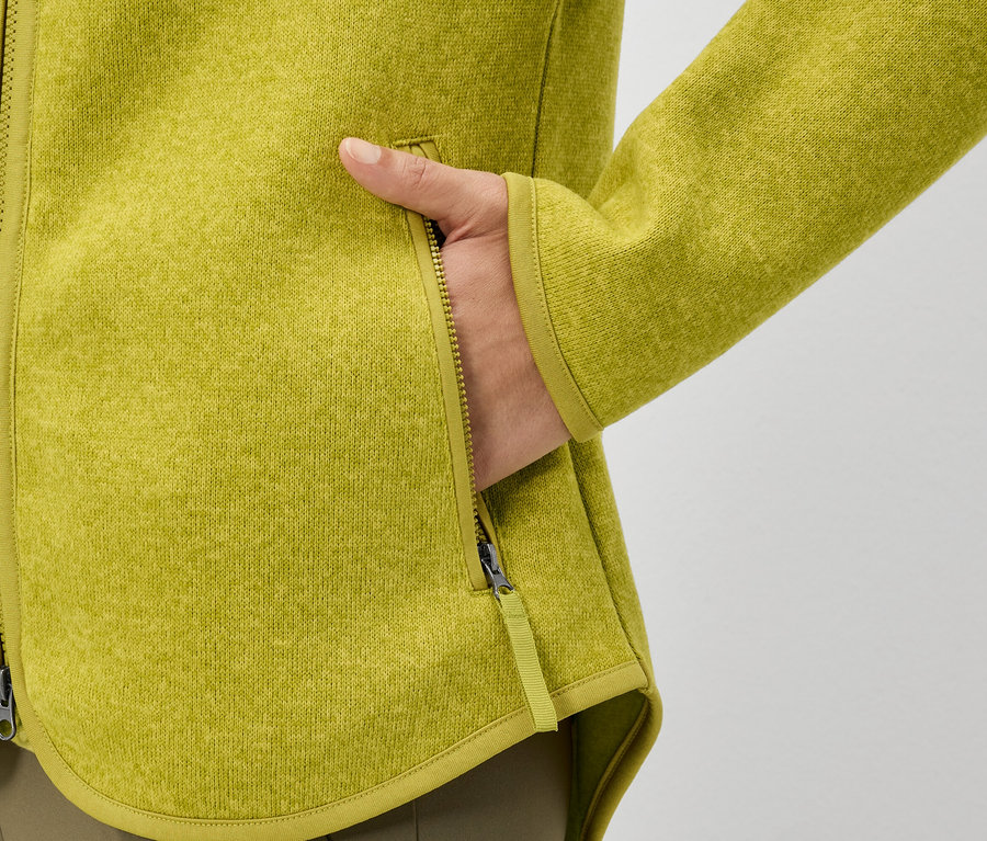 Ruka vo vrecku žltej flísovej bundy.