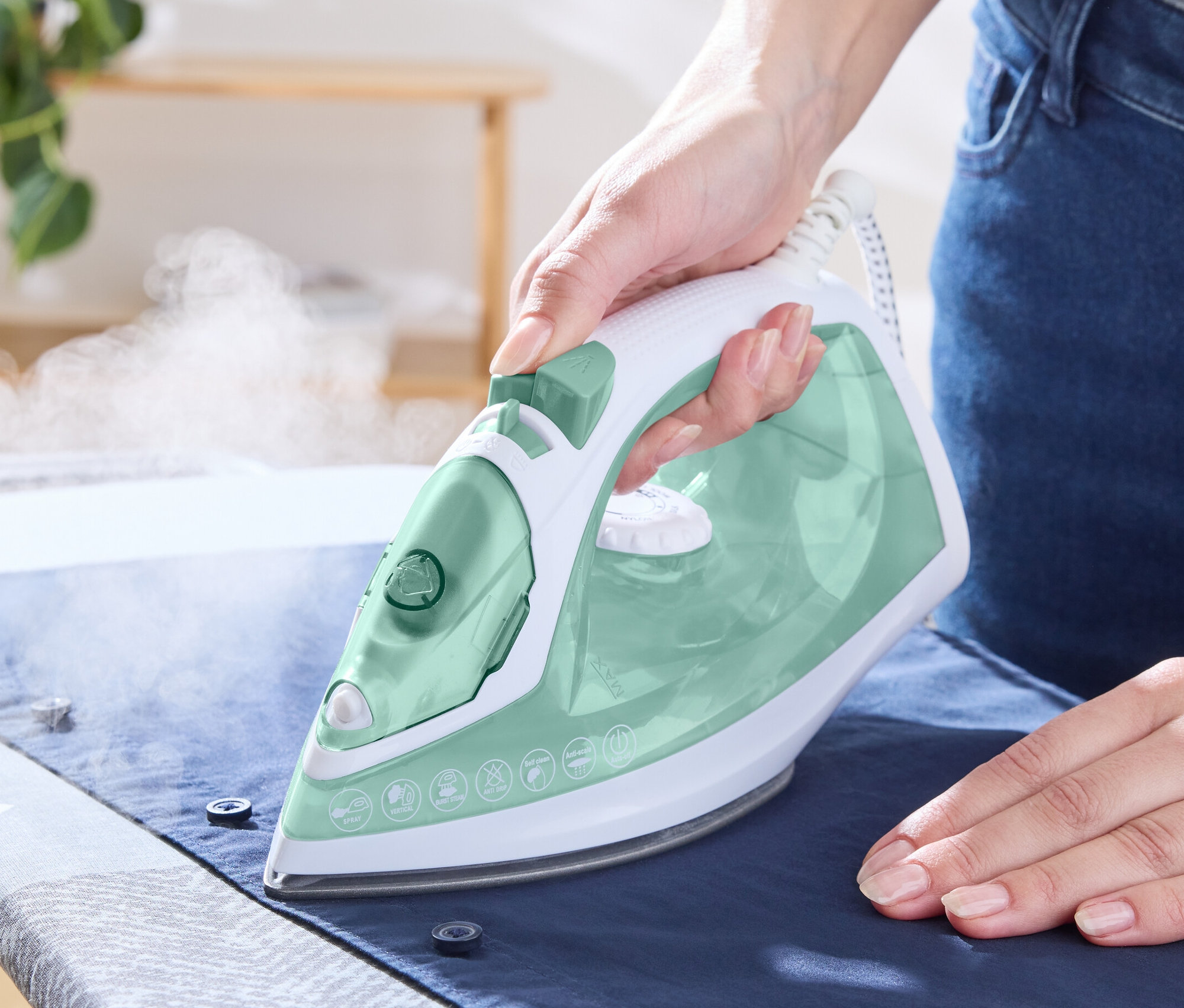 Žena žehlí košeľu parnou žehličkou.