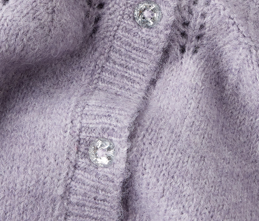 Detail fialového pleteného kardigánu s dvoma striebornými gombíkmi.