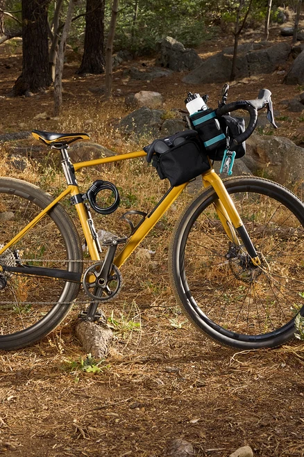 Žltý bicykel s čiernymi taškami a príslušenstvom v lese.