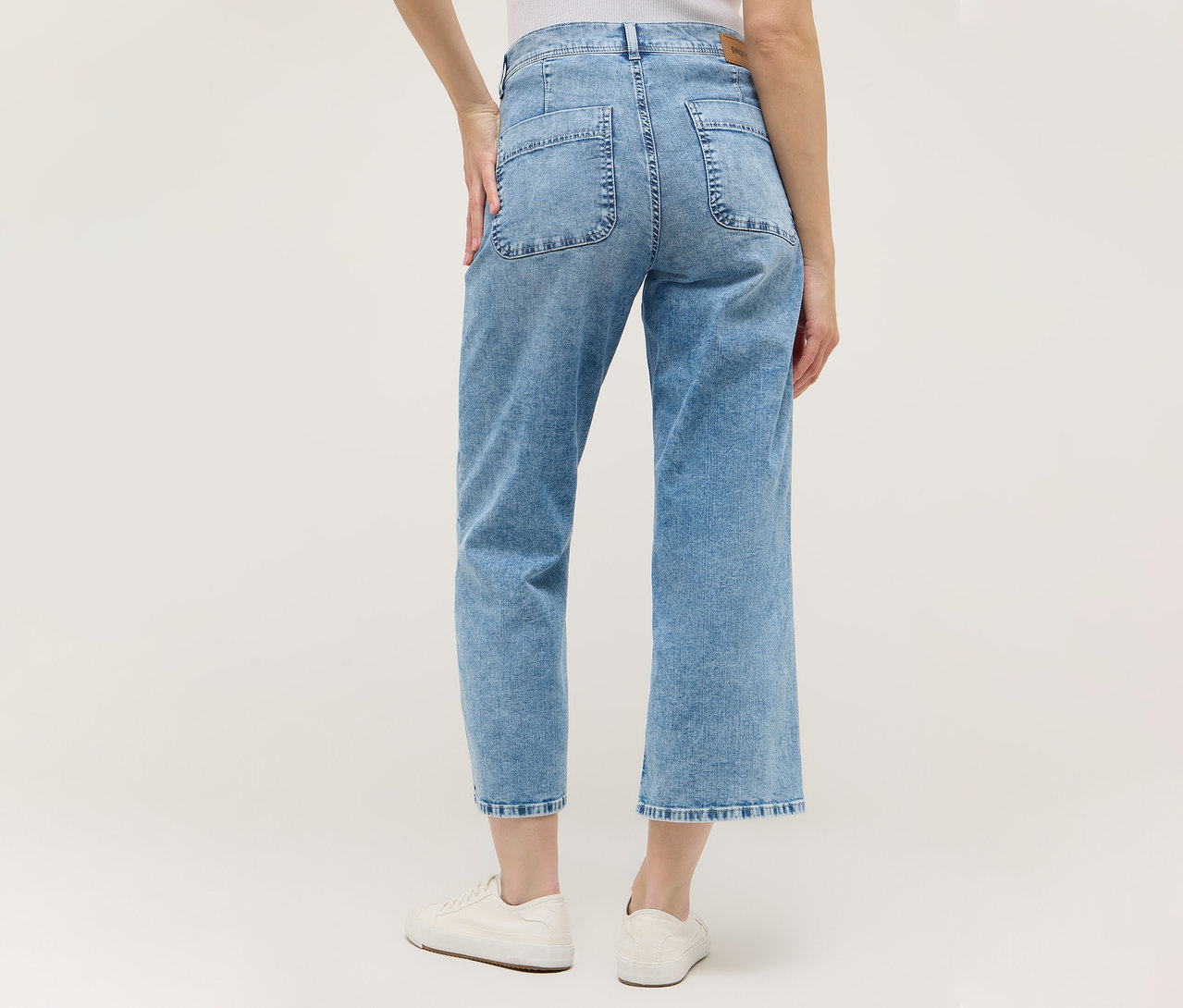 Pohľad zozadu na ženu v svetlomodrých nohaviciach Angels Denim »Linn Smart« Culotte a bielych topánkach.