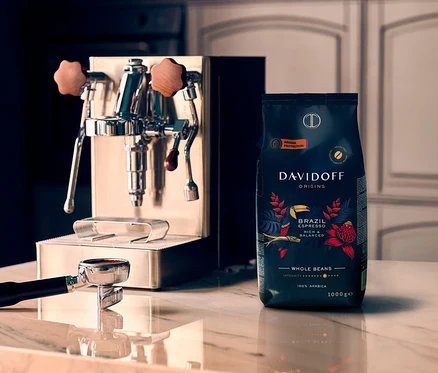 Espresso kávovar a balenie DAVIDOFF CAFÉ ORIGINS Brazil - 3 x 1 kg Ganze Bohne stoja na mramorovom povrchu.