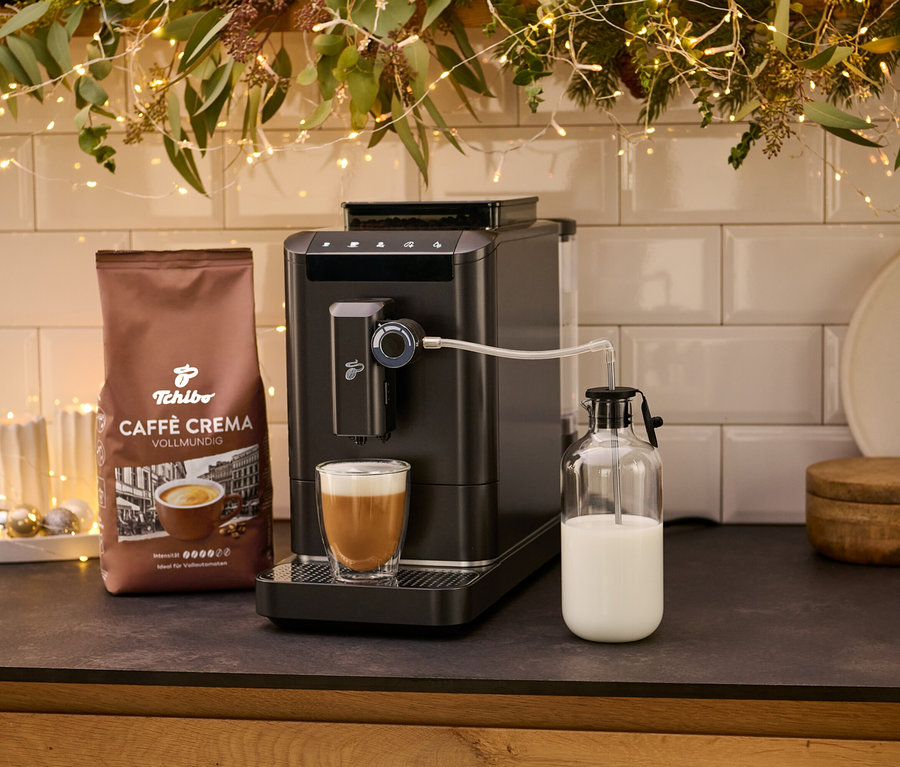 Kávovar »Esperto 2 Milk« Granite Black so šálkou kávy a balíčkom kávy Crema. Mlieko je uložené v sklenenej nádobe.