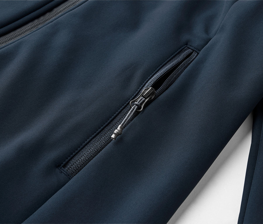 Detailný záber na tmavomodrú bundu s vreckom na zips a zipsom na golieri.