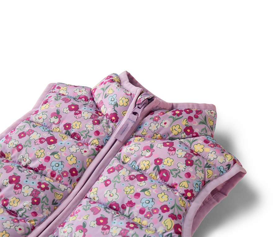 Detailný záber na fialovú, prešívanú vestu s kvetinovým vzorom a zipsom.