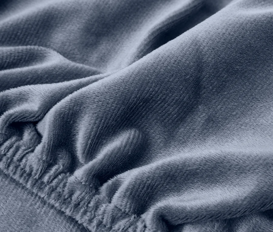 Detail modrošedej plyšovej látky s mäkkými záhybmi a elastickým okrajom.