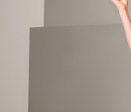 Žena pózuje v červenom tričku a tmavomodrých bermudách.