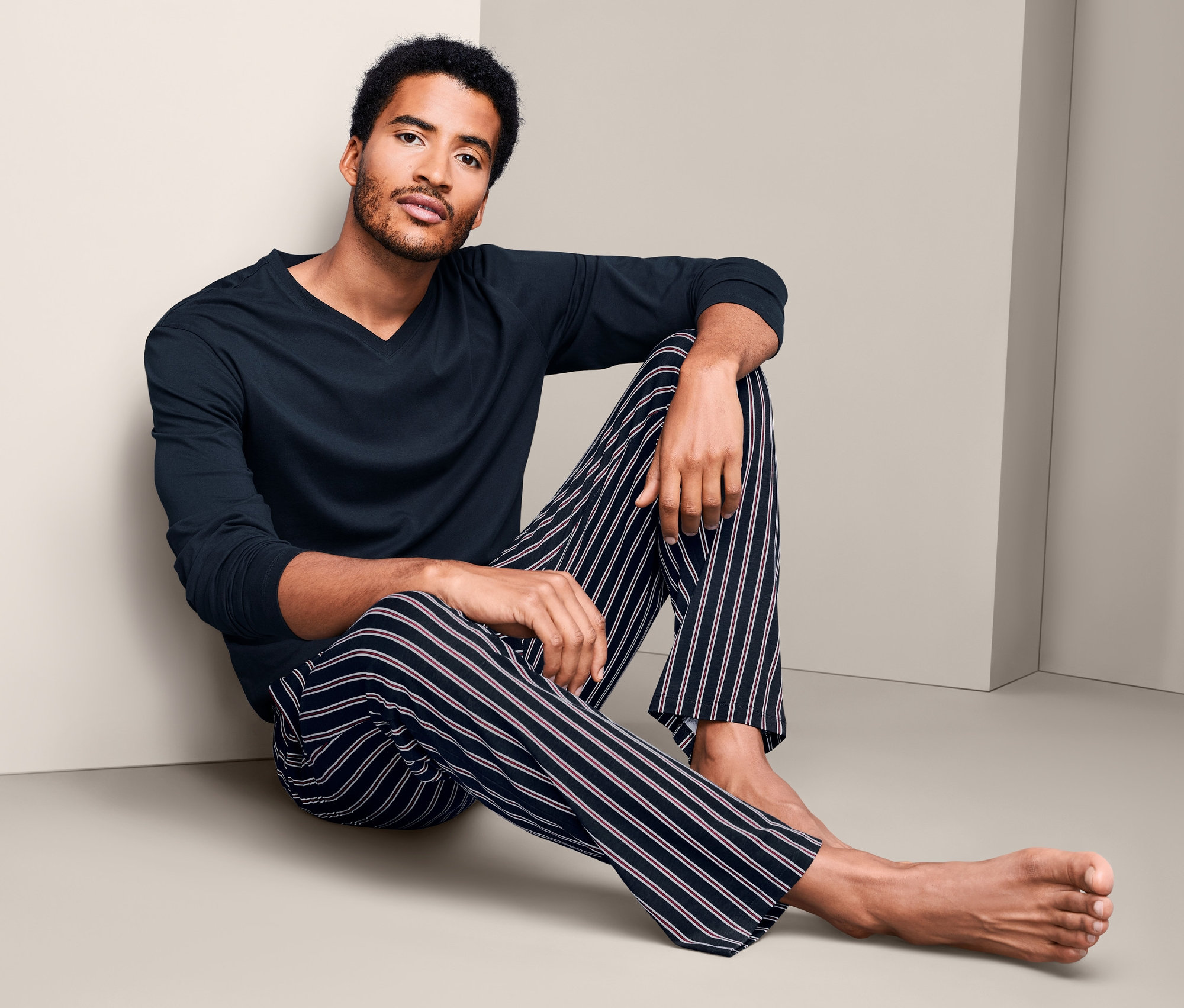 Muž sedí na podlahe v pyžame.