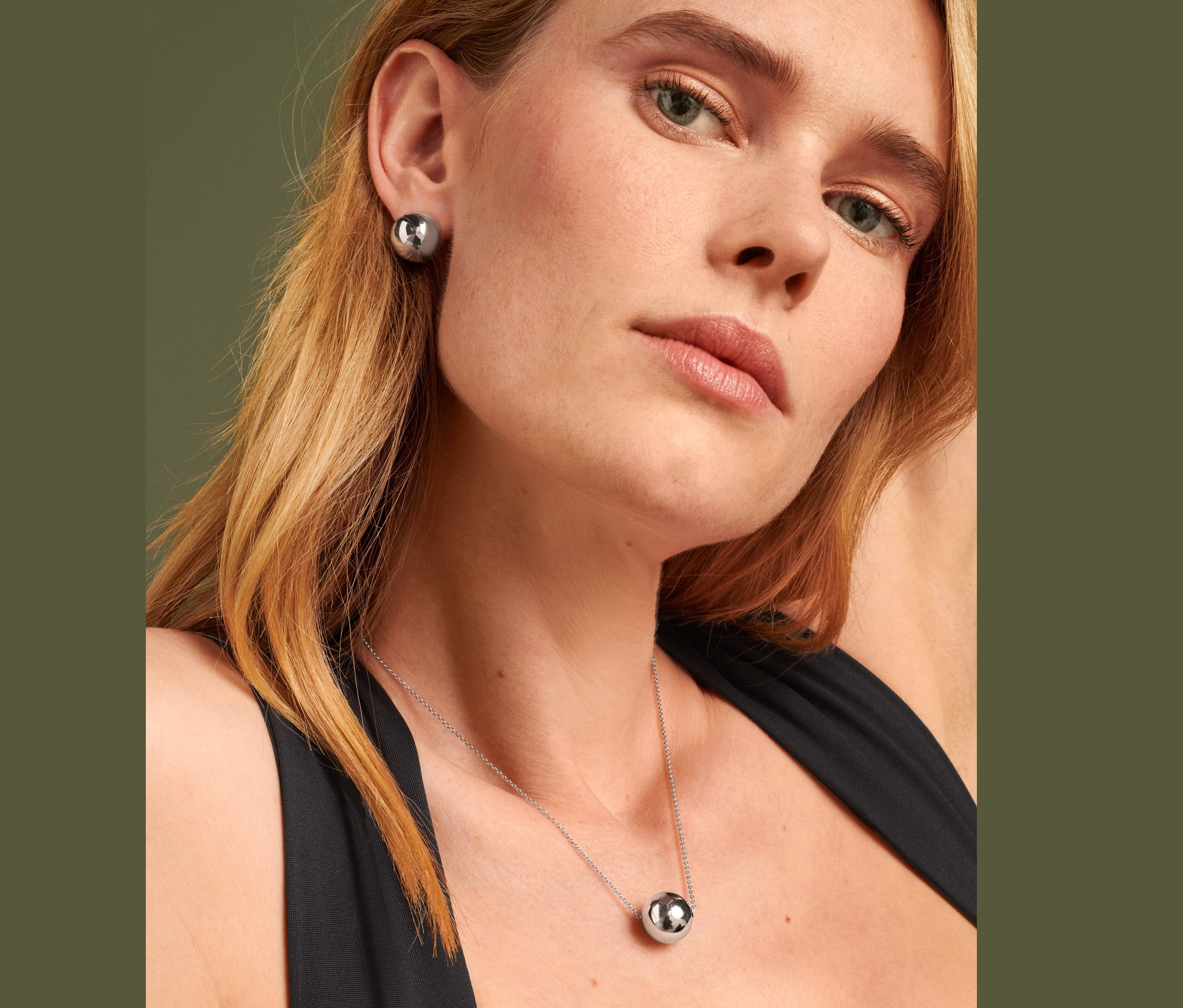 Blondínka s napichovacími náušnicami Globe a retiazkou Globe.