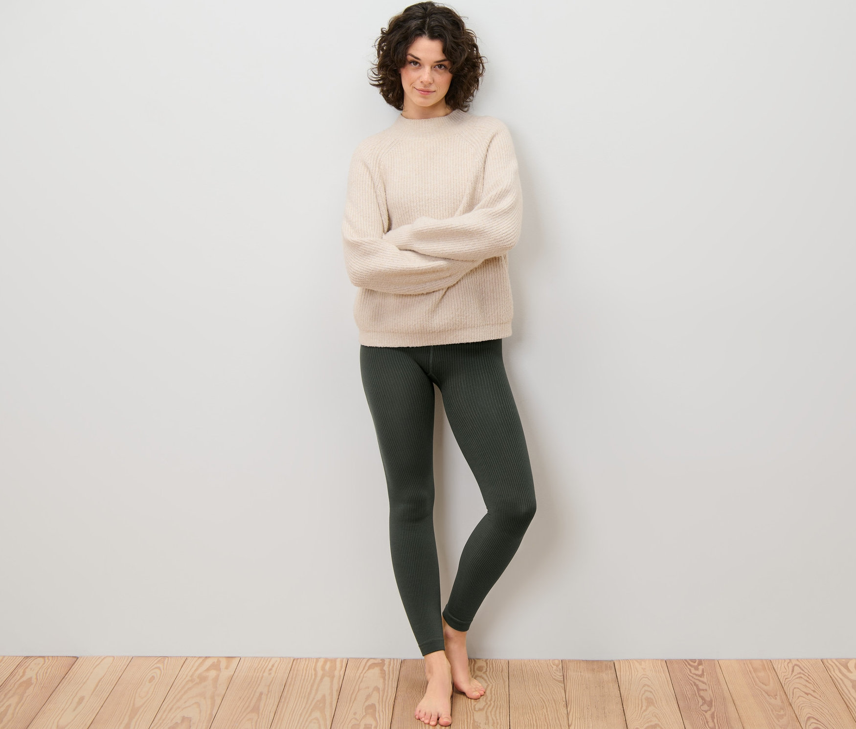 Žena stojí s prekríženými rukami a má na sebe rebrované termo legínsy.