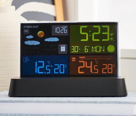 Meteorologická stanica riadená rádiovým signálom s farebným LCD displejom stojí na knihe.