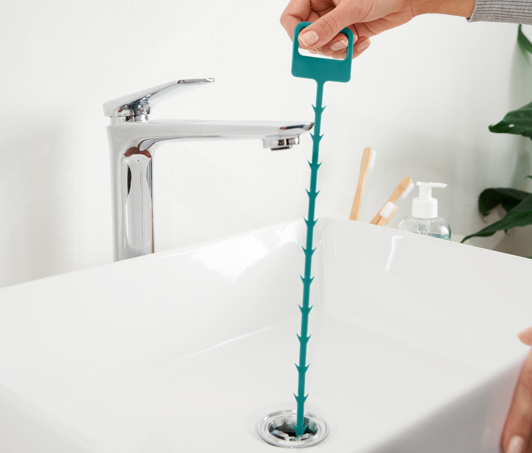 Ruka vkladá čistič odtoku do umývadla.