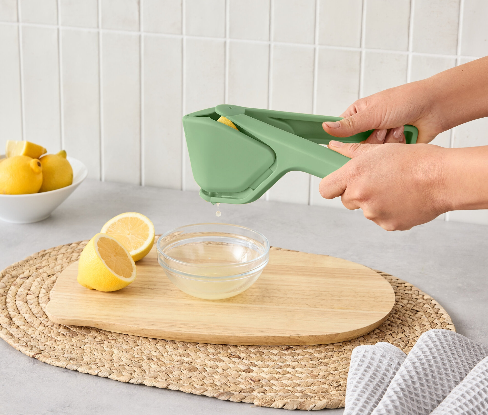 Žena používa priestorovo úsporný lis na citrusy na vylisovanie citróna do misky.