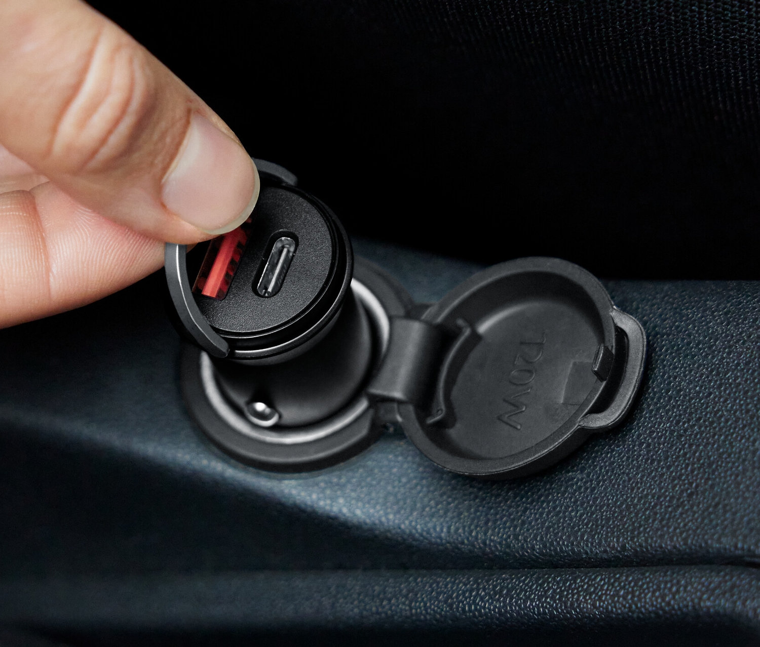 Ruka vkladá rýchlonabíjačku do auta do zásuvky.