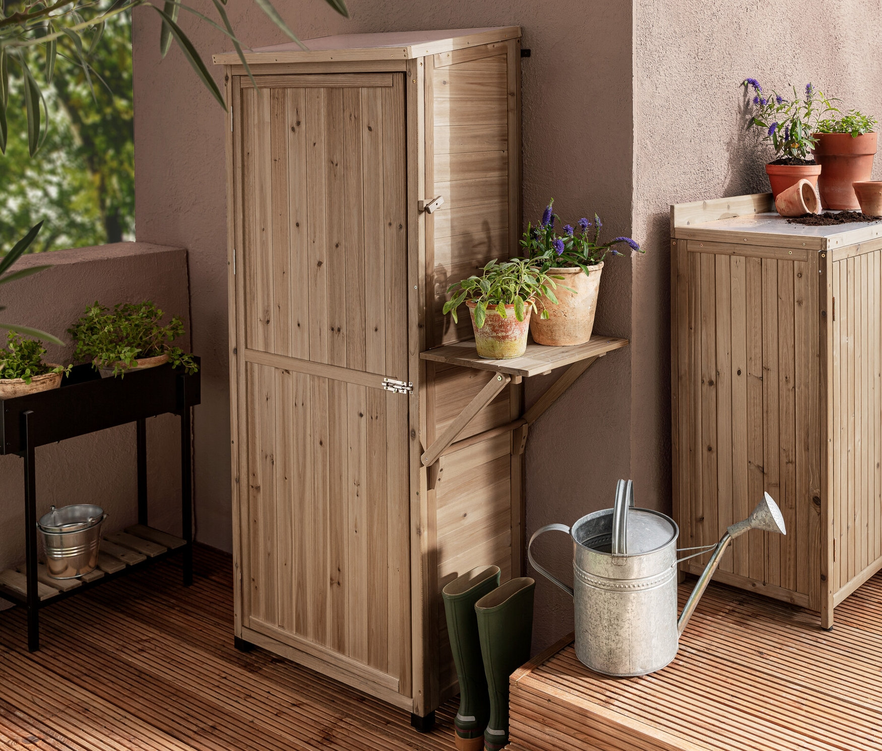 Dve záhradné skrine »Tinus«, jedna veľká so sklopným regálom naboku a jedna malá, a rastlinná konzola »Elin« na drevenej terase.