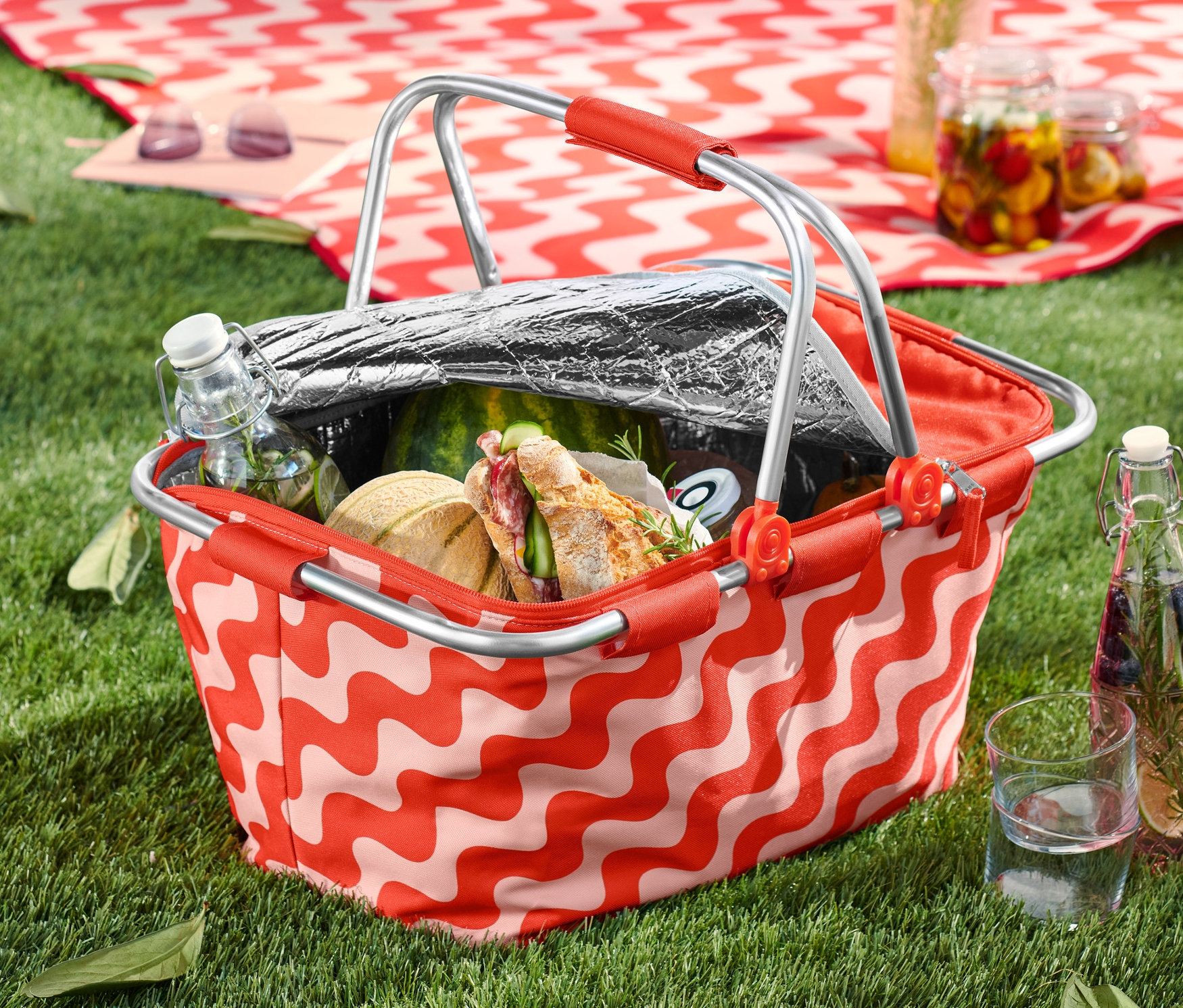 Na tráve stojí chladiaci košík s jedlom a pitím.