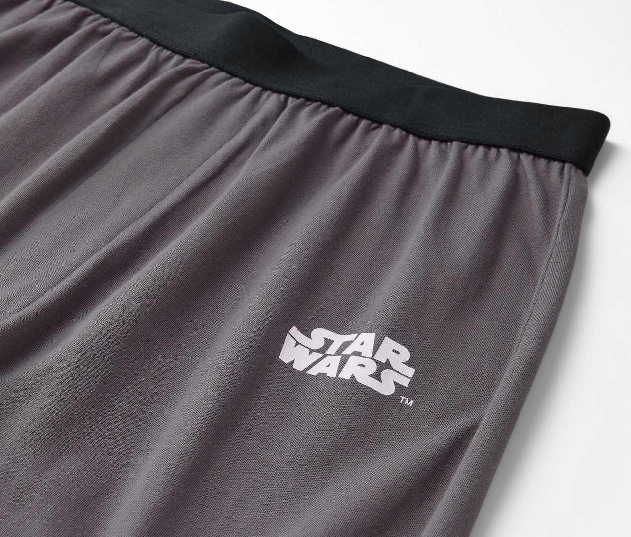 Detail sivých nohavíc s čiernym pásom a logom Star Wars.