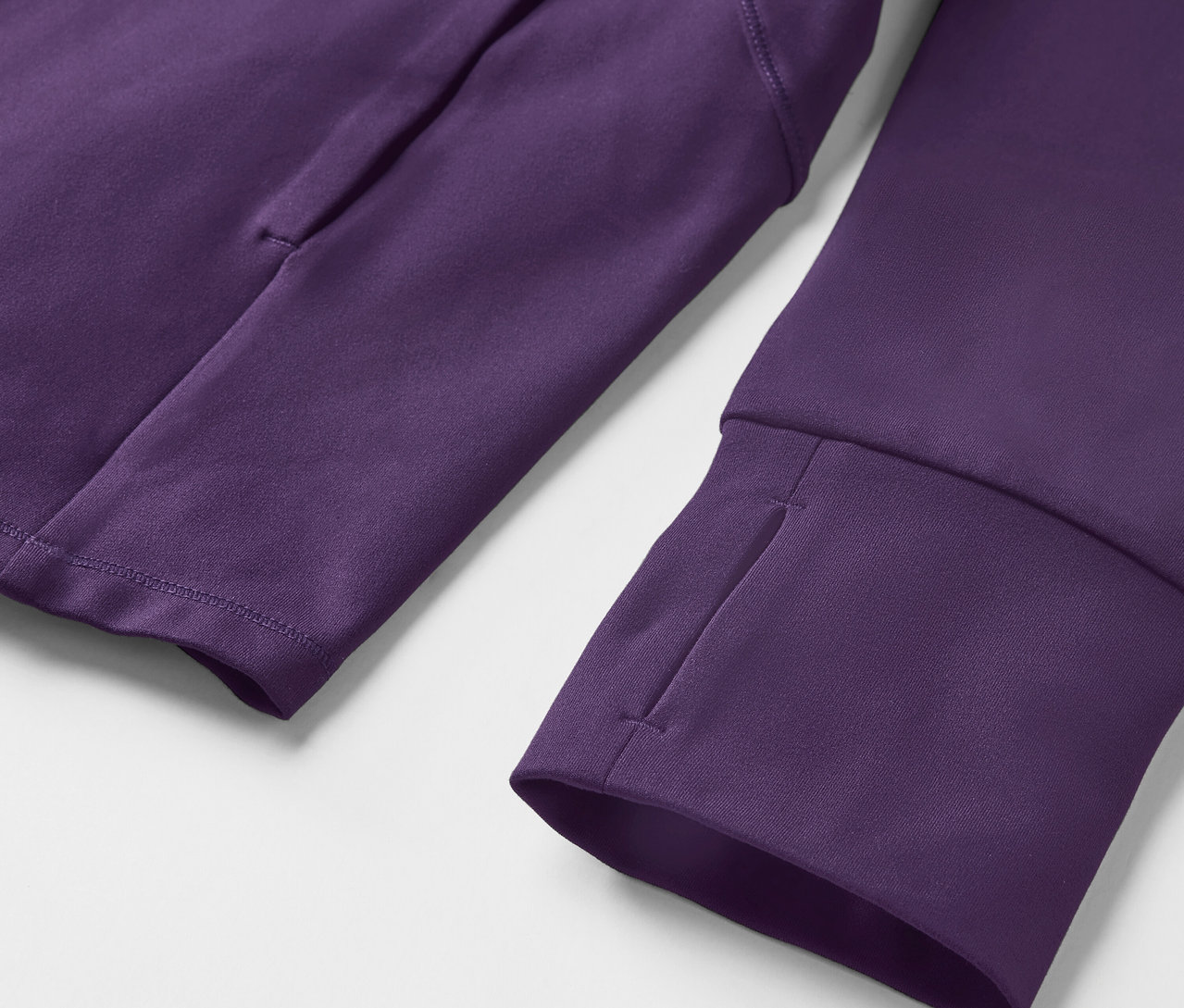 Detail fialovej mikiny s dlhým rukávom s otvormi na palce a vreckom na ramene.