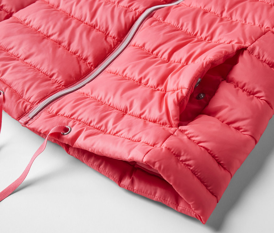 Detail prešívanej vesty s kapucňou. Vesta je ružová a má strieborný zips.