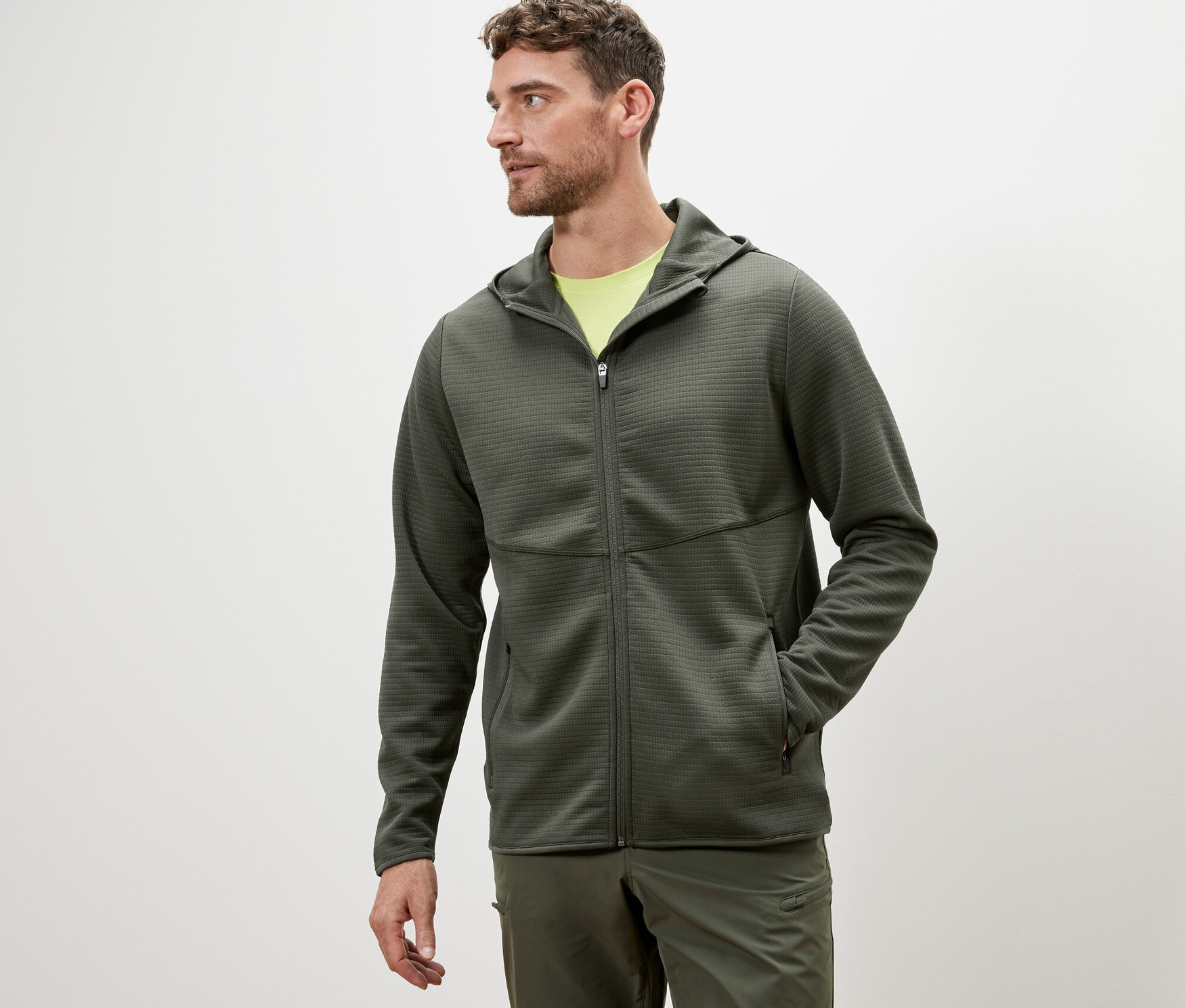 Muž má na sebe funkčnú bundu khaki.