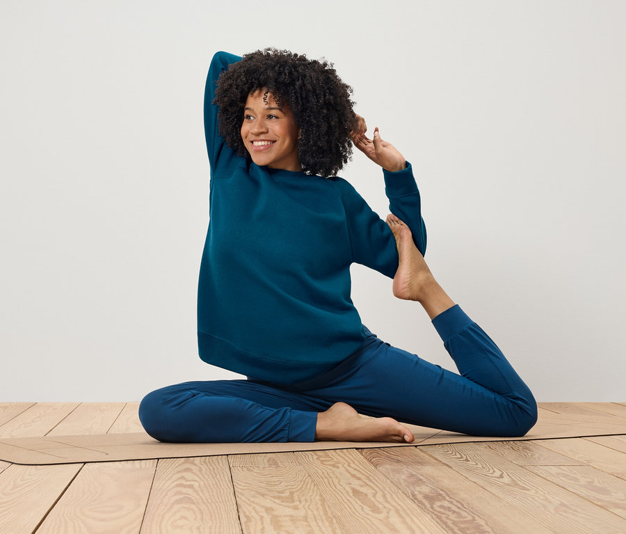 Afroameričanka v modrej súprave cvičí jogu na podložke.