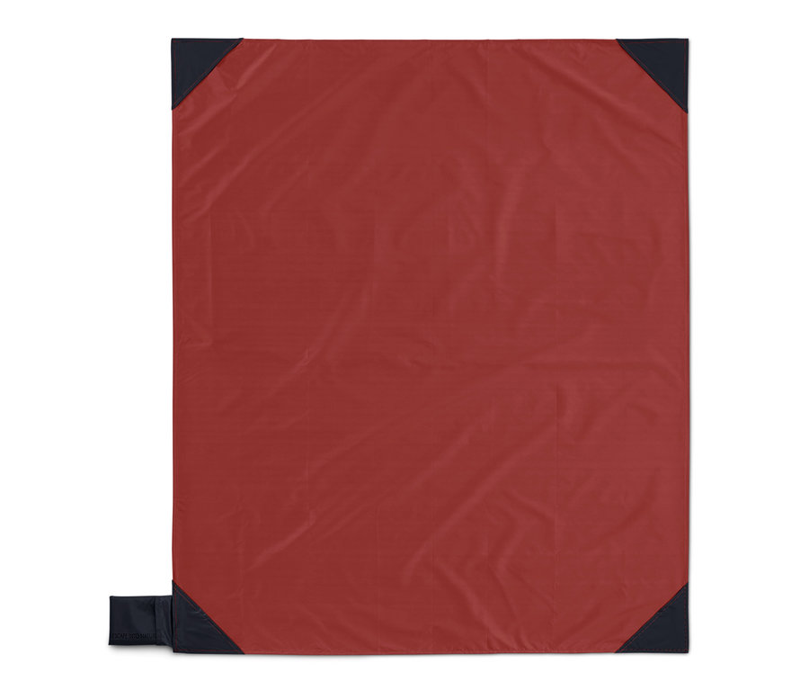 Červená malá deka na piknik s tmavomodrými rohmi.