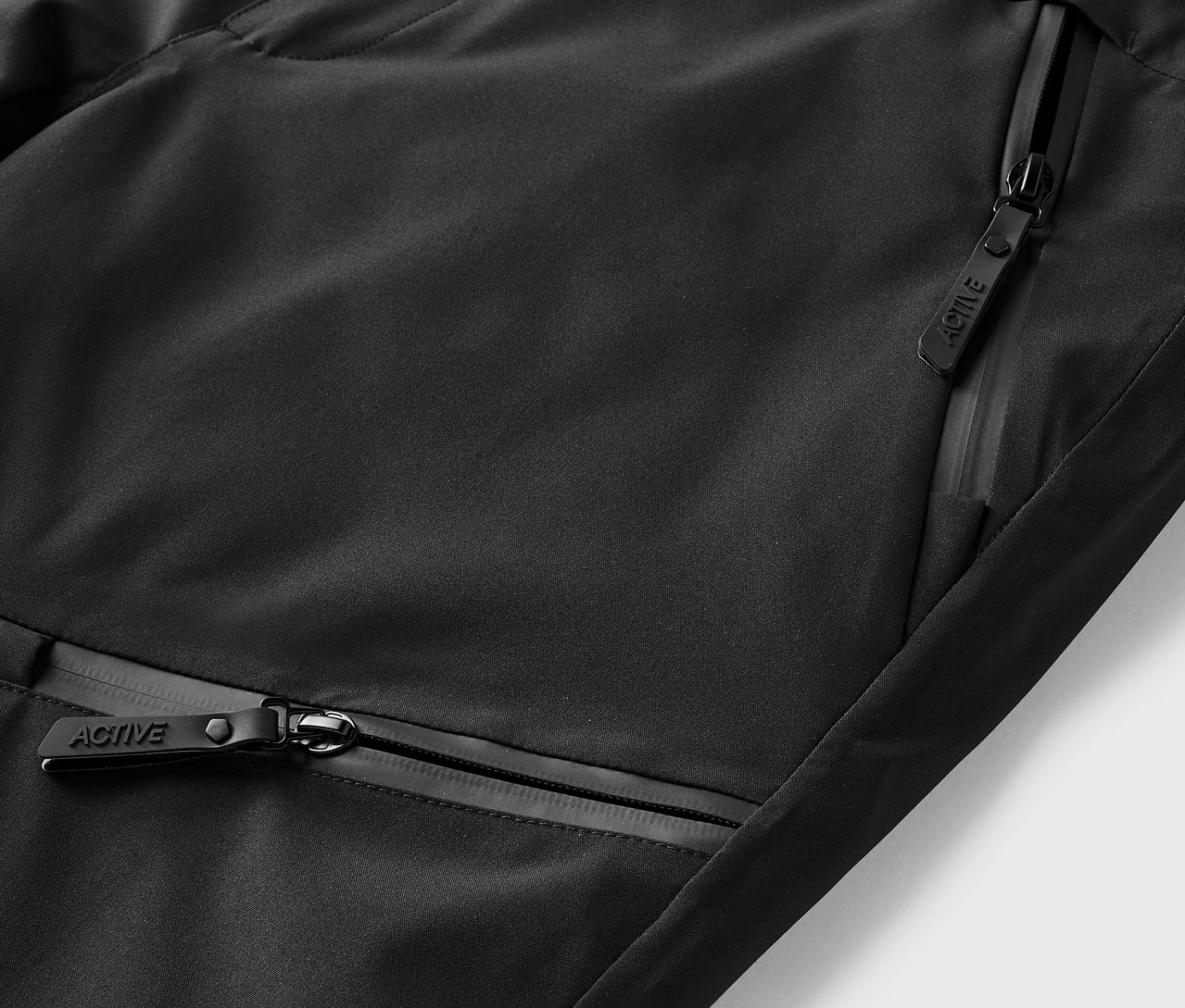 Detail čierneho športového oblečenia s vreckami na zips.