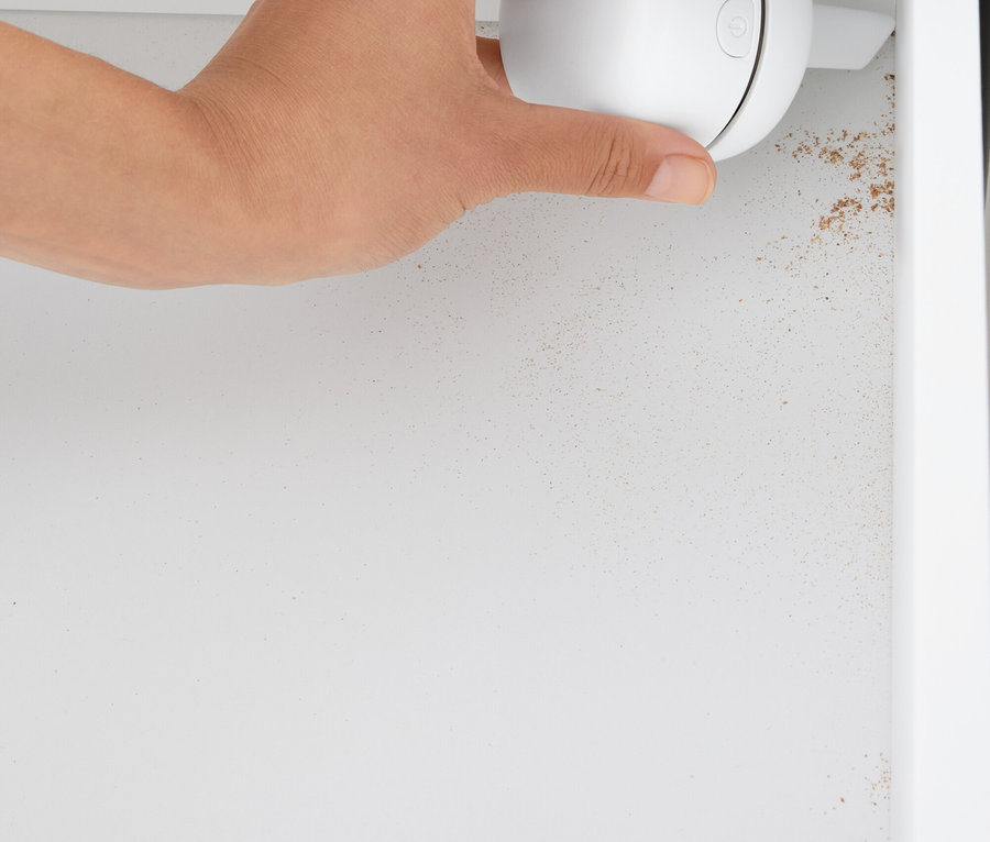 Ruka drží biely guľový čistič v bielej skrinke.