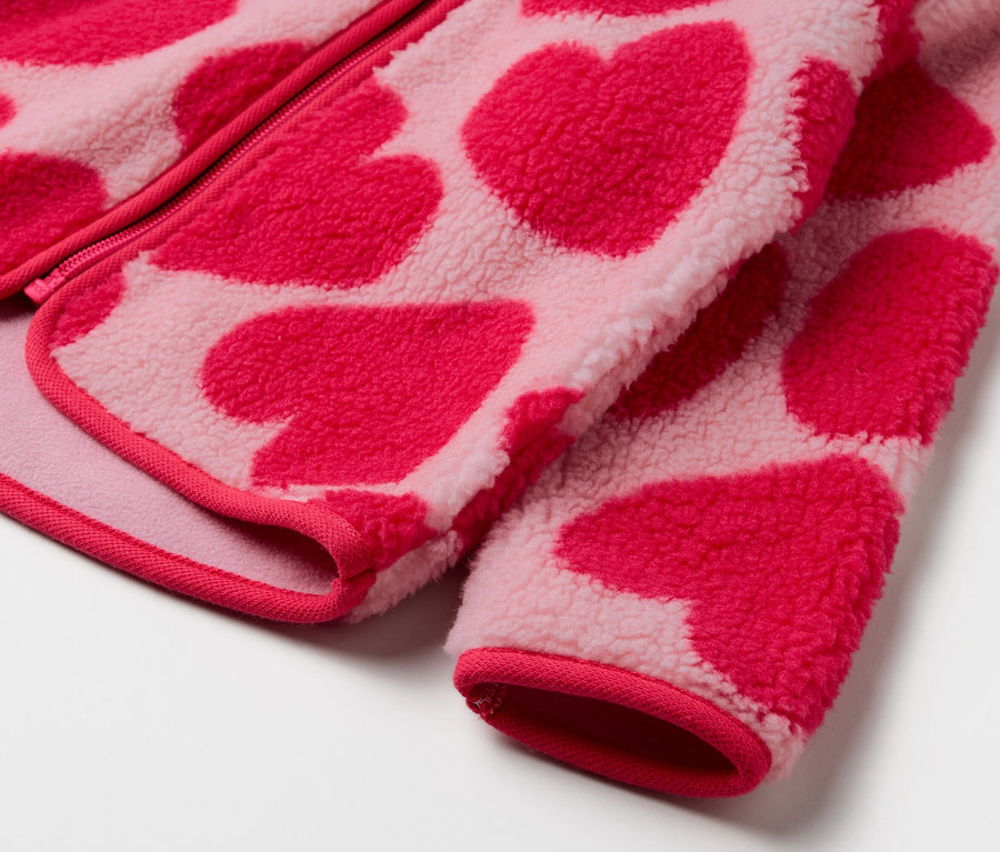 Detail ružovej fleecovej bundy so vzorom červených srdiečok.