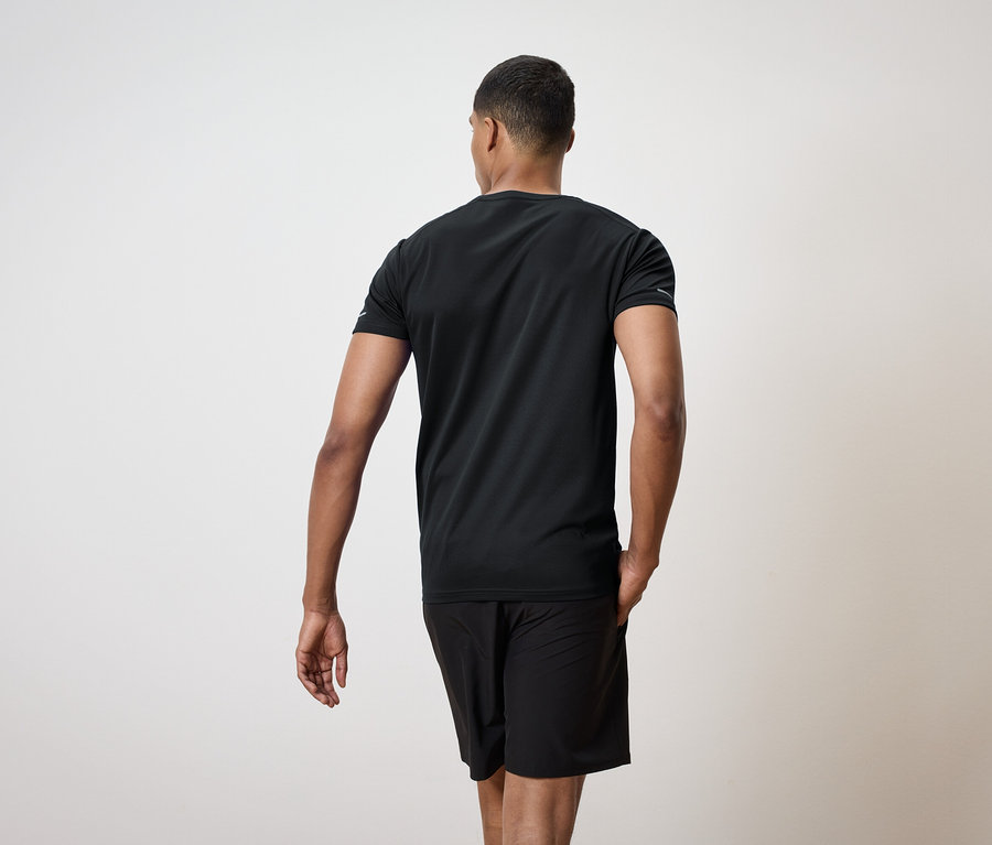 Muž zozadu v čiernom tričku a šortkách.