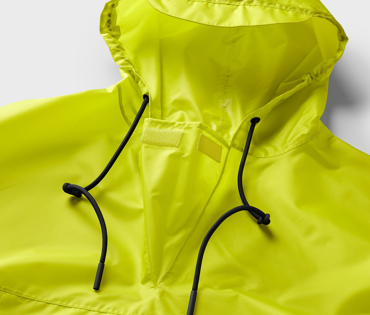 Detailný záber na neónovožlté pončo do dažďa s kapucňou a čiernymi sťahovacími šnúrkami.