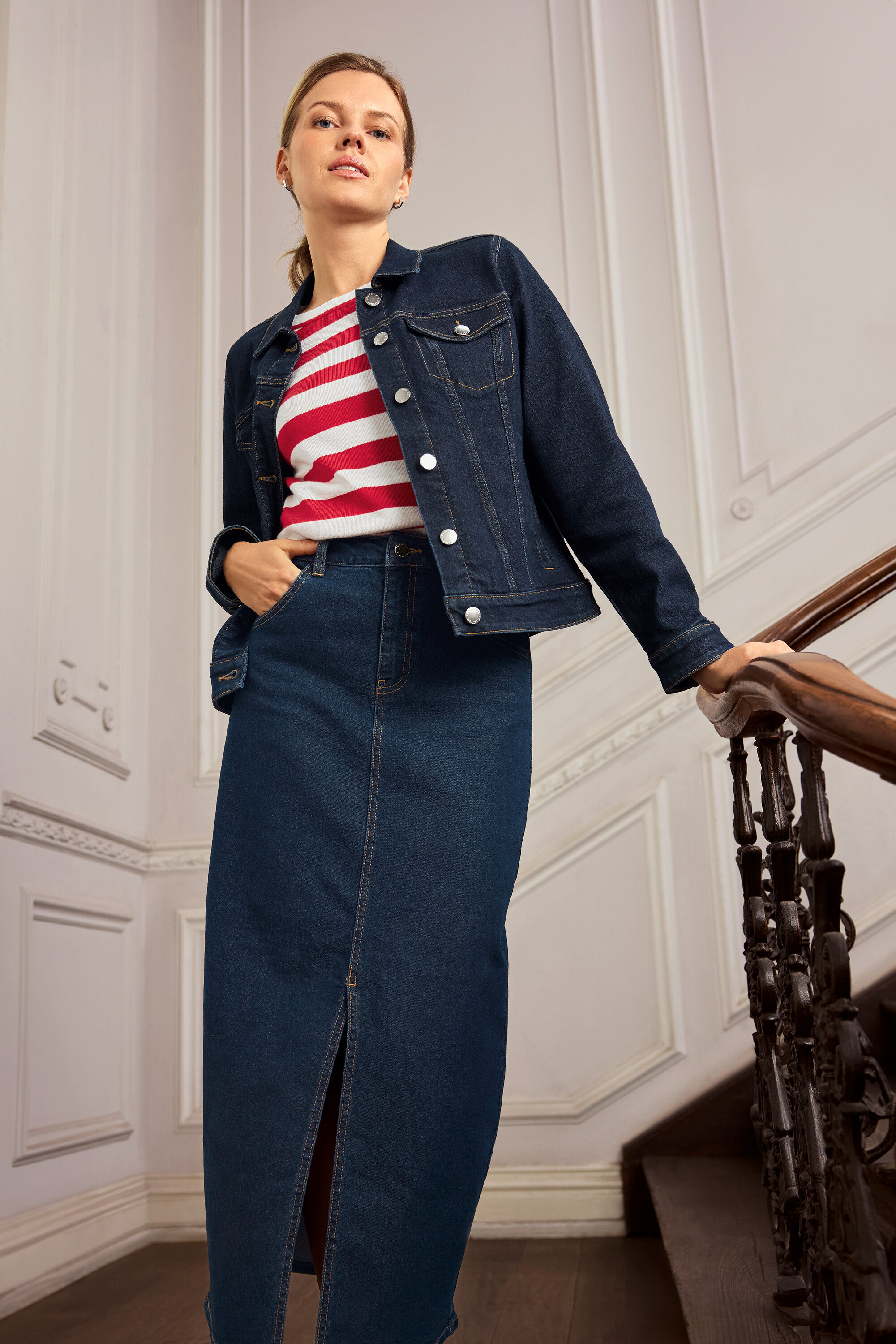 Žena v džínsovej bunde a sukni pózuje na schodoch. Má na sebe náušnice 925 Silver Creolen Hexagon.