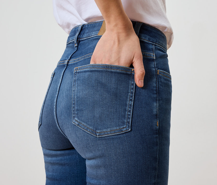 Žena má ruku vo vrecku na zadku modrých džínsov.