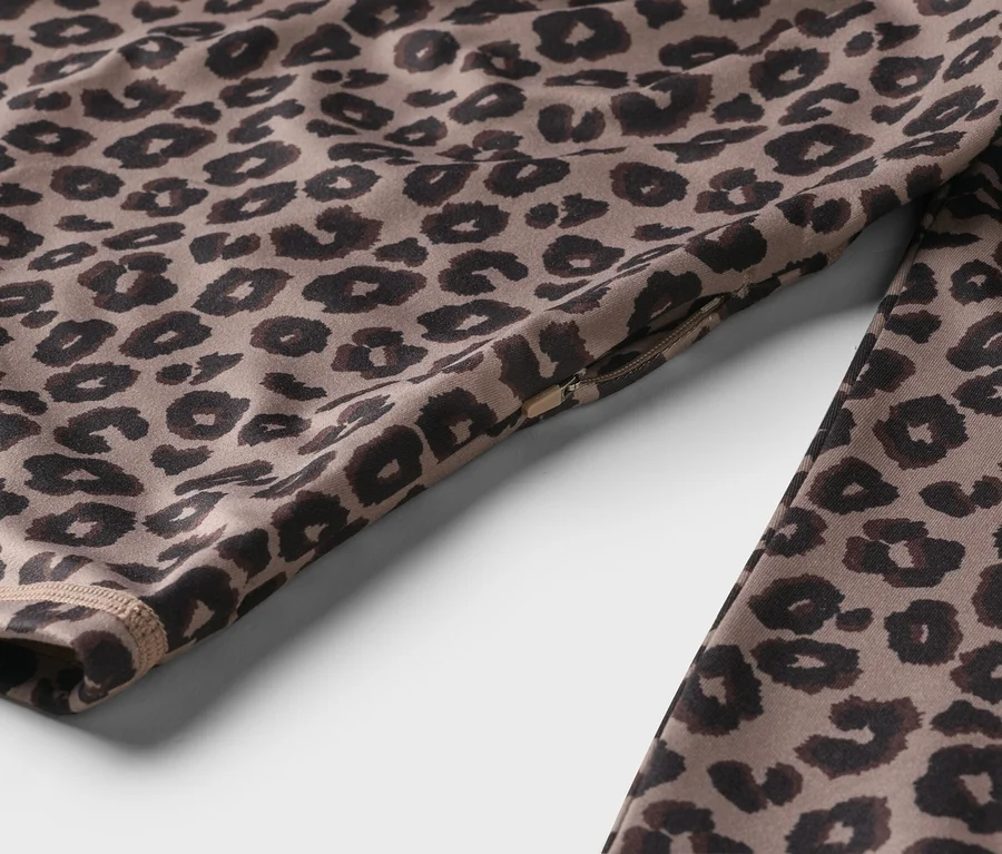 Detailný záber športového oblečenia s leopardím vzorom a detailom zipsu.