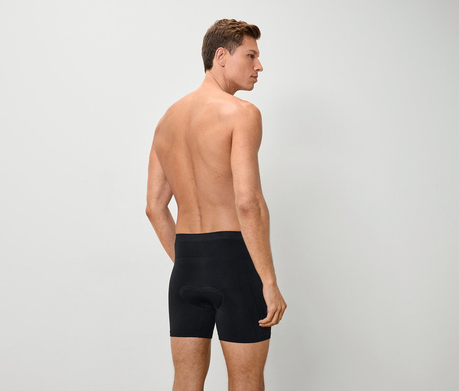 Pohľad zozadu na muža s nahým vrchom tela v čiernych boxerkách.
