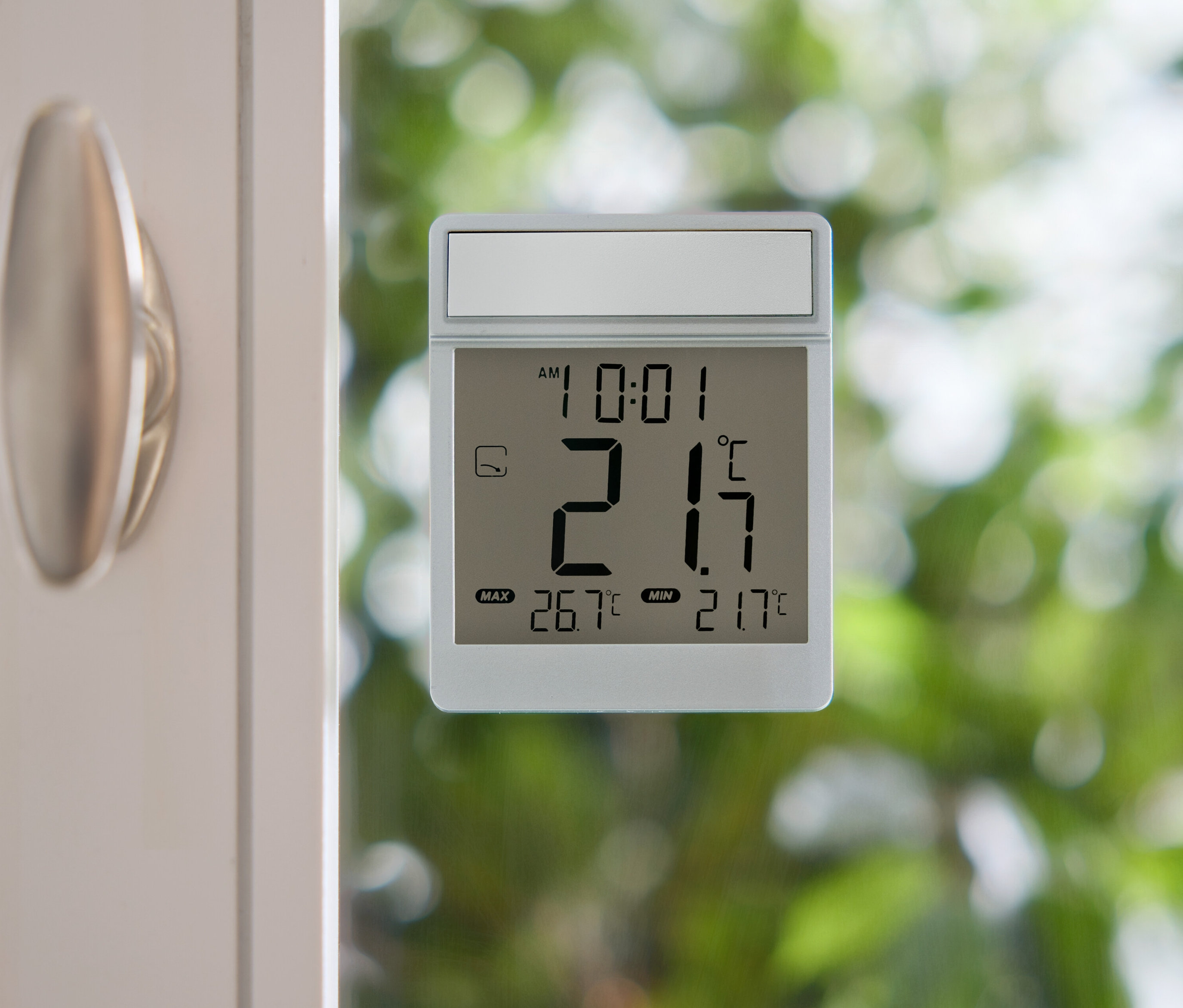 Digitálny teplomer ukazuje 21,7 stupňov Celzia na okennom skle.