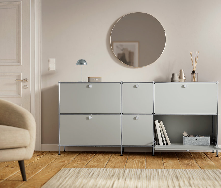 Sivá skrinka so šiestimi priehradkami stojí vedľa dverí a kresla.