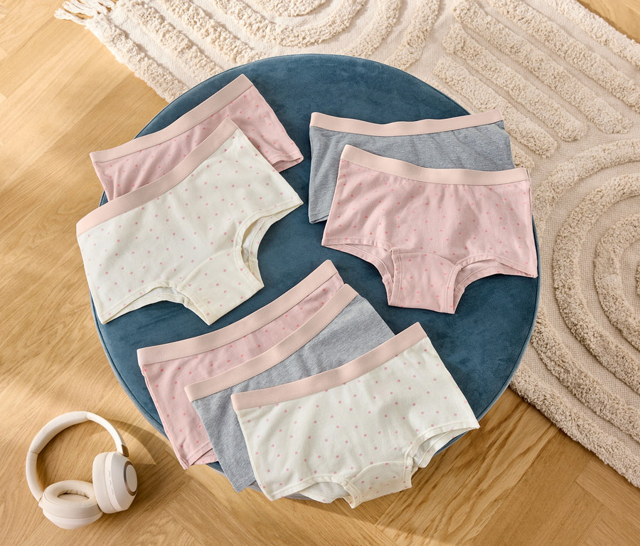 Na modrej stoličke leží šesť párov dámskych šortiek v sivej, ružovej a bodkovanej farbe, vedľa nich sú slúchadlá.