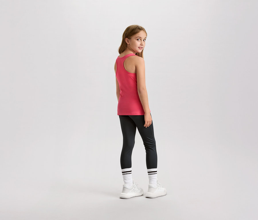 Mladé dievča sa pozerá cez plece, má na sebe ružový tielko, legíny a biele tenisky.