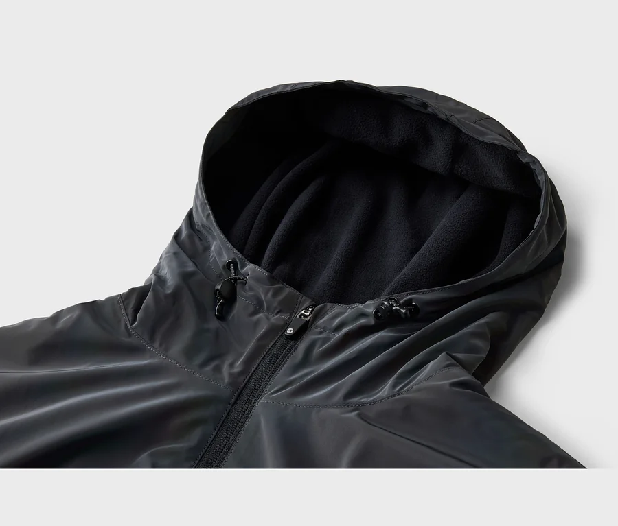 Detail tmavosivej bundy s kapucňou, ktorá je podšitá čiernym flísom. Bunda má zips a šnúrky so zarážkami na kapucni.