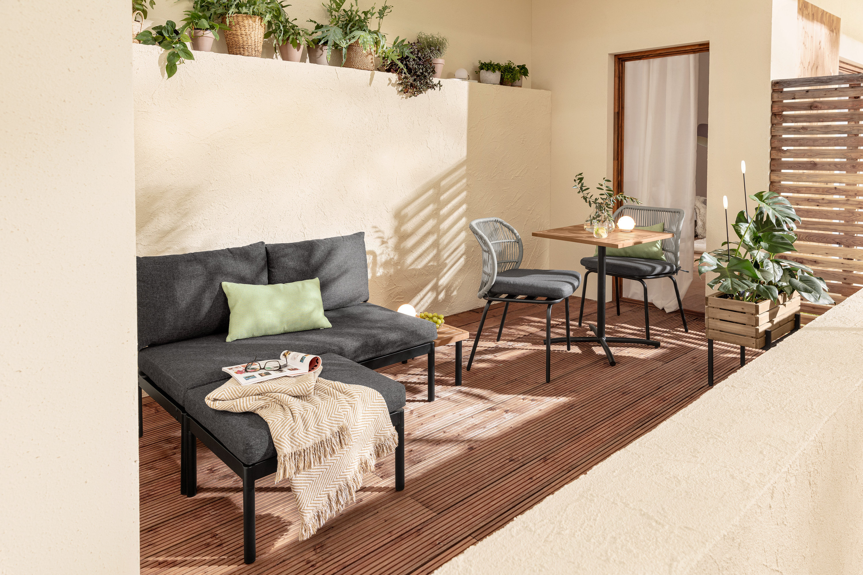 Zariadenie balkóna s variabilnou súpravou balkónového lounge nábytku Elin, stolíkom, stoličkami s textilným výpletom, 2 vankúšmi do exteriéru, kvetináčom a solárnymi zapichovacími svietidlami.