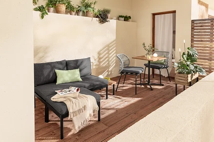 Zariadenie balkóna s variabilnou súpravou balkónového lounge nábytku Elin, stolíkom, stoličkami s textilným výpletom, 2 vankúšmi do exteriéru, kvetináčom a solárnymi zapichovacími svietidlami.