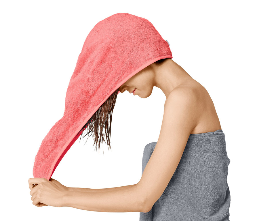 Žena si dáva na mokré vlasy uterákový turban.