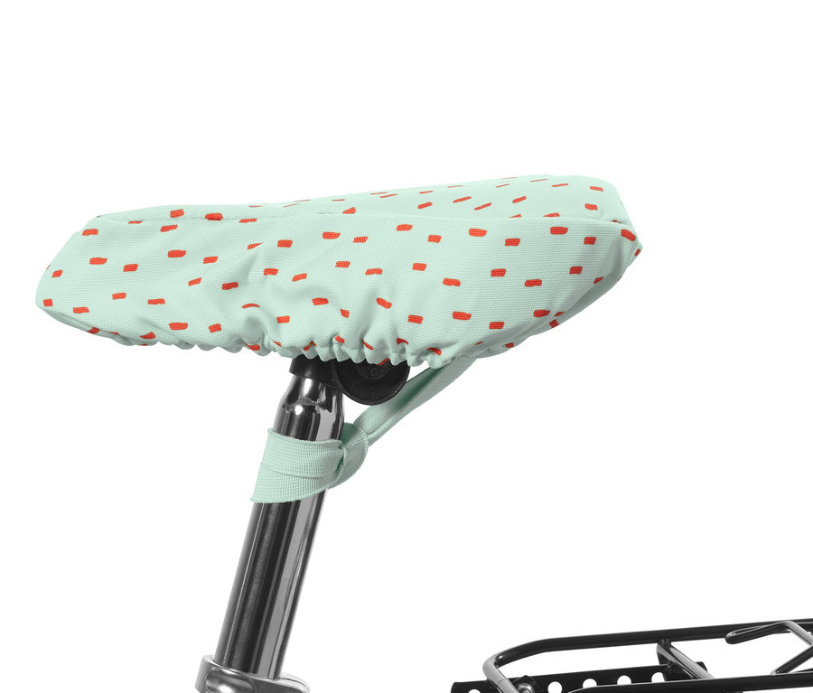 Detský poťah na sedadlo bicykla je mätovo zelený s červenými obdĺžnikmi.