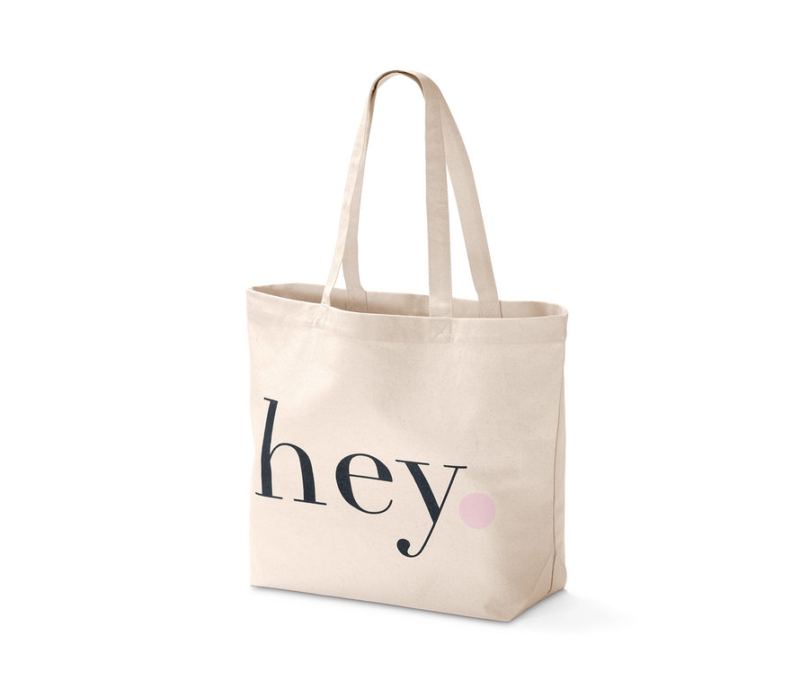 Plátenná nákupná taška s čiernym nápisom hey a ružovou bodkou.