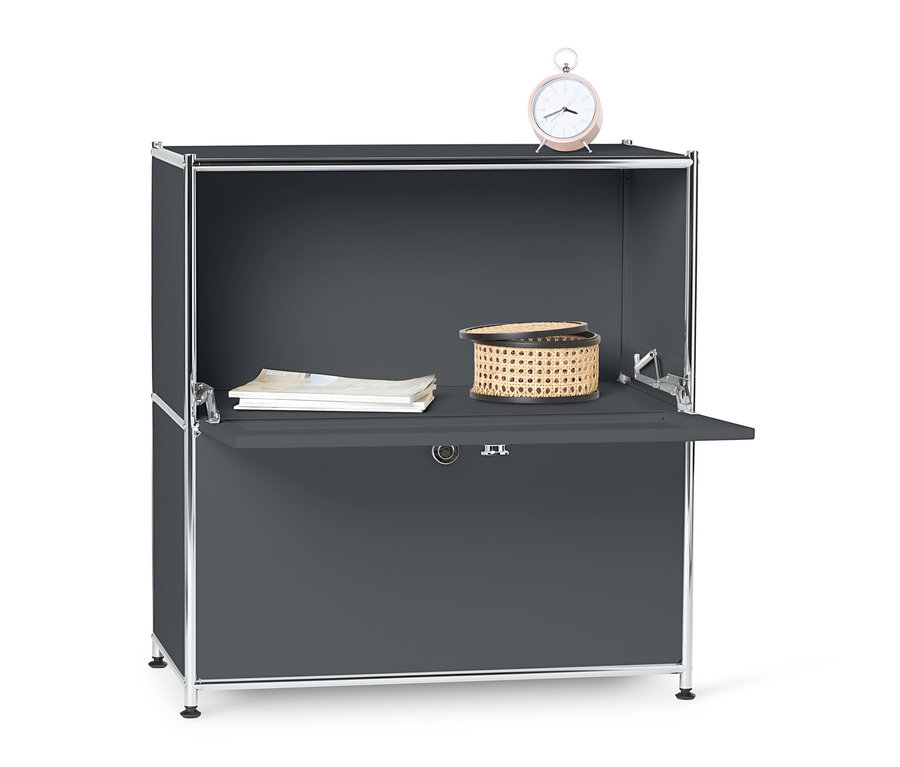 Sivá kovová odkladacia skrinka »CN3« s výklopnými priehradkami, na ktorej leží prútený košík, dokumenty a ružový budík.
